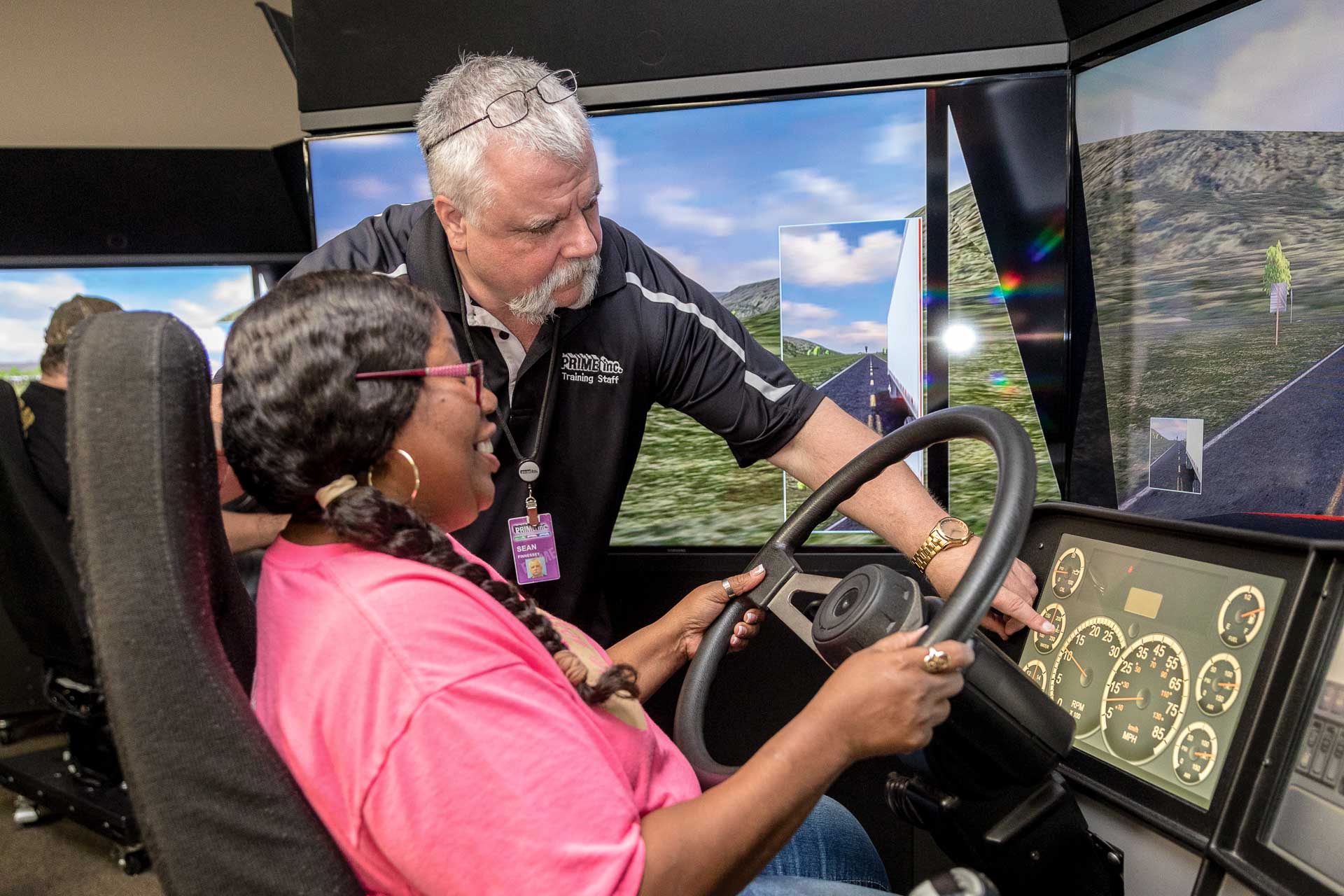 A Prime driving instructor showing a student driver something during a driving simulation.
