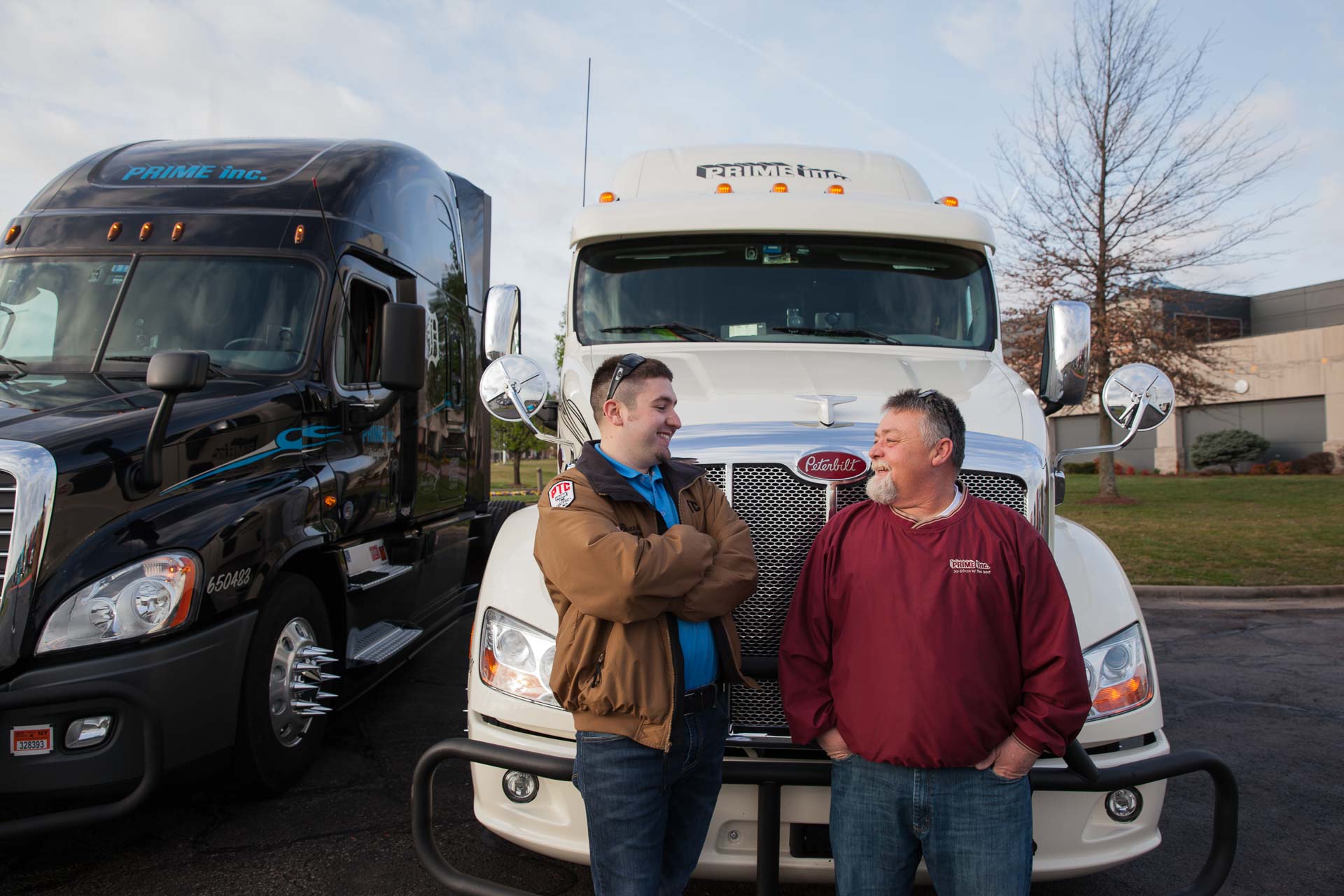 A team of Prime truck drivers talking in front of their newly leased semi-truck.