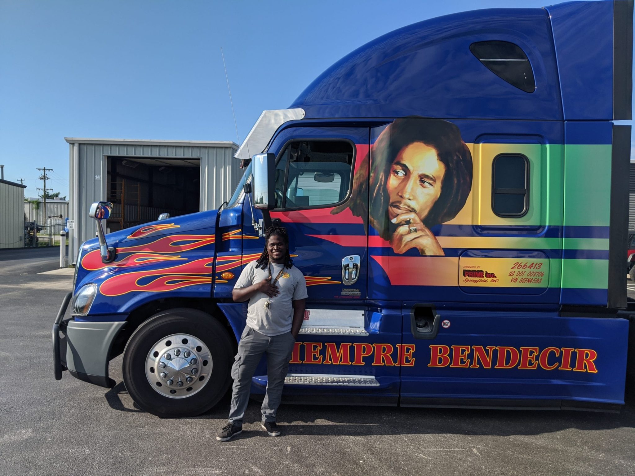 Prime driver stands next to Bob Marley themed truck.