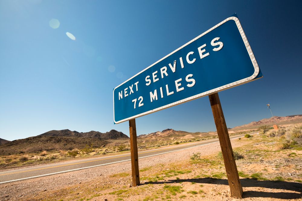 Service sign beside a desert road says "next services 72 miles."