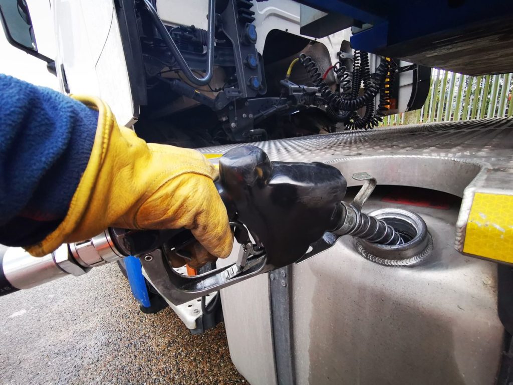 Closeup of a semi-truck driver fueling up with diesel fuel. Closeup of hand on diesel pump. 