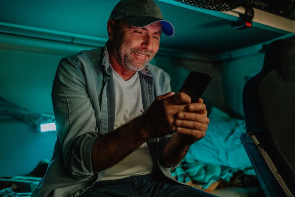 Man inside semi-truck cab talks to his family on the phone.