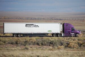 A Prime reefer truck drives down a highway and you can see the horizon in the distance.