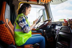 A female truck driver plans her schedule for the day inside her truck.